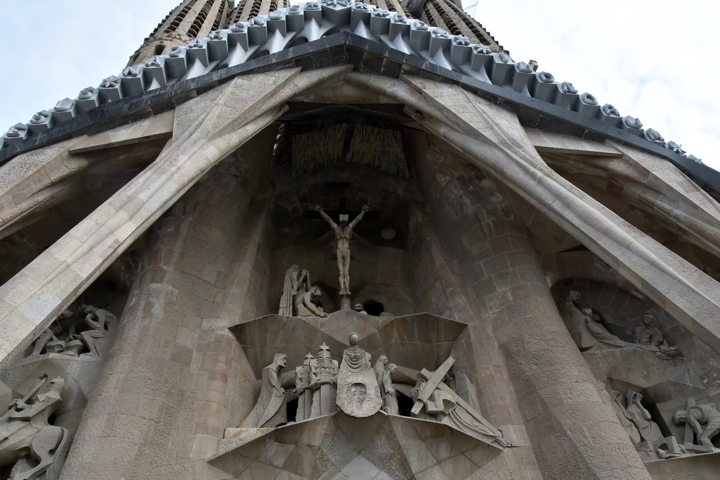 The Passion façade portal and sculpture under cloudy skies.